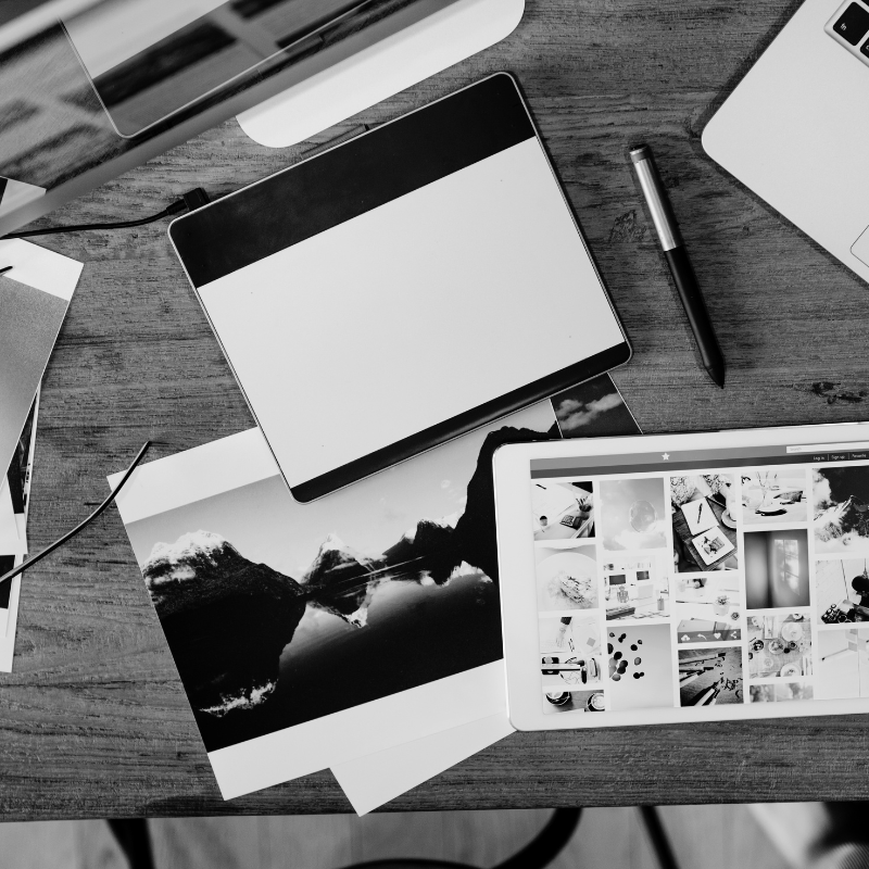 Bureau de travail avec tablette graphique, impressions photo et tablette affichant une galerie d’images.